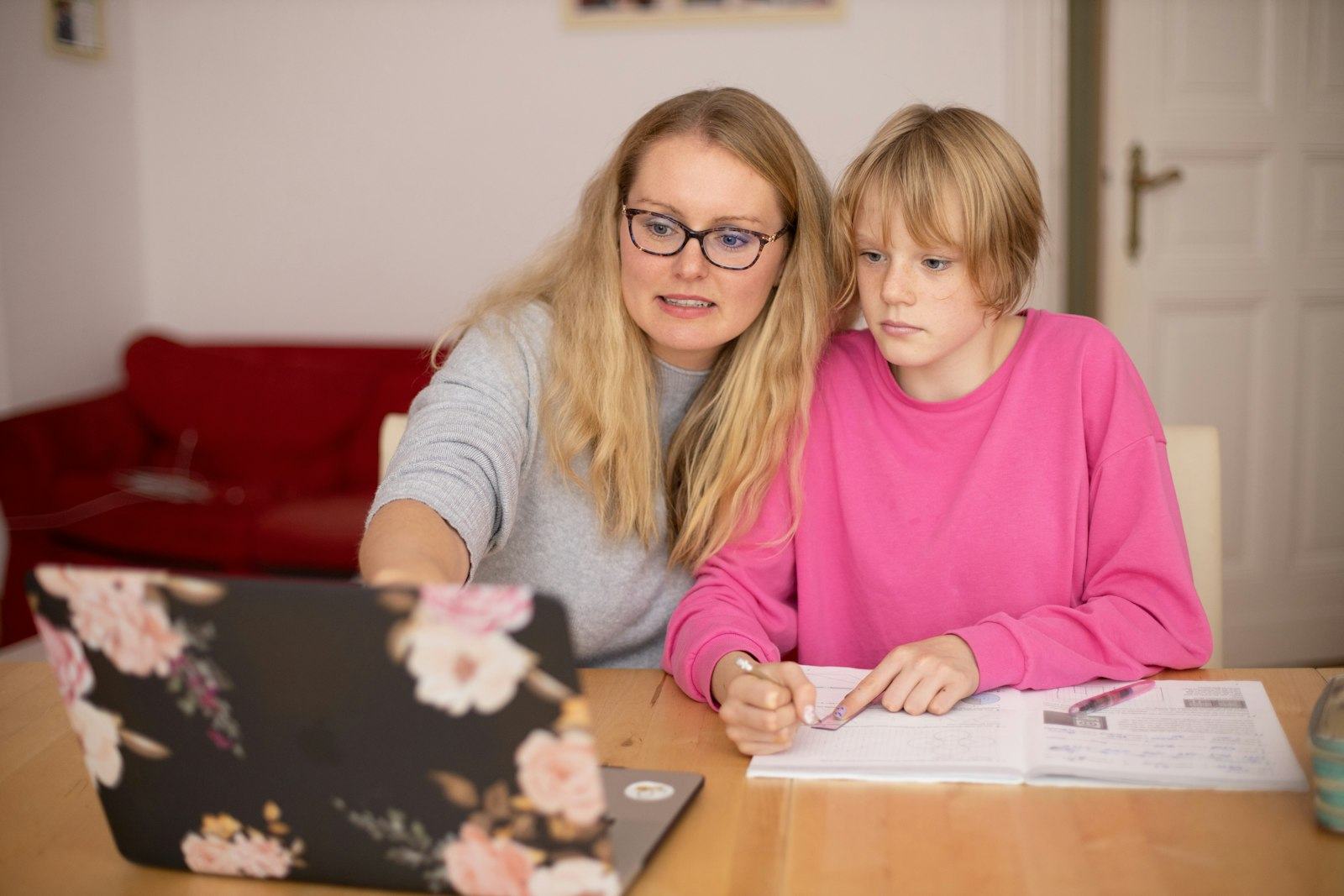 A tutor and a girl look at a laptop screen together at a table.