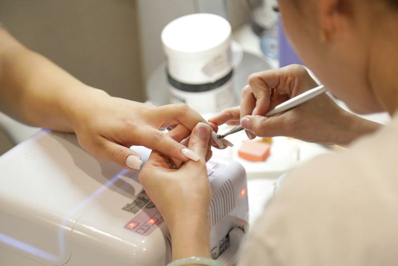 A nail tech carefully painting gel polish during a manicure