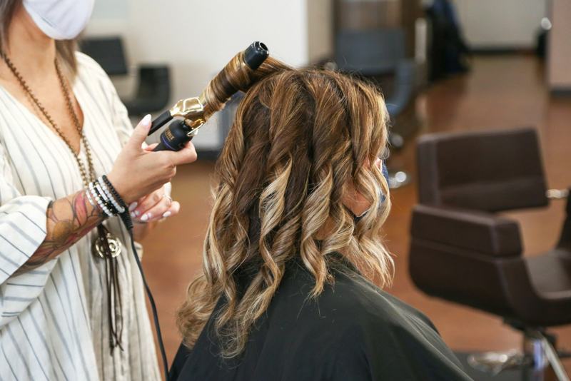 A stylist shaping soft curls with a curling iron in the studio
