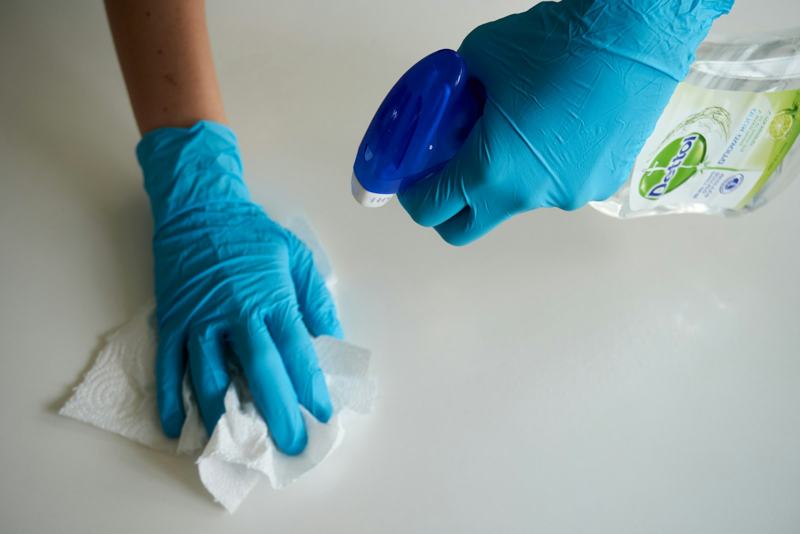 Gloved hands spraying and wiping a white counter