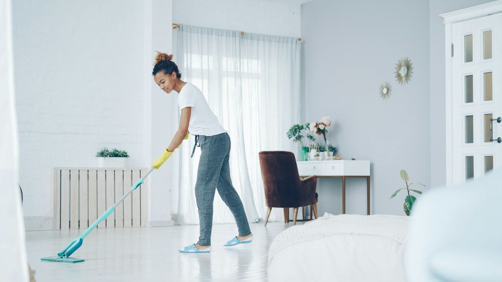 A FreshNest-style cleaner mopping the floor of a bright white living room