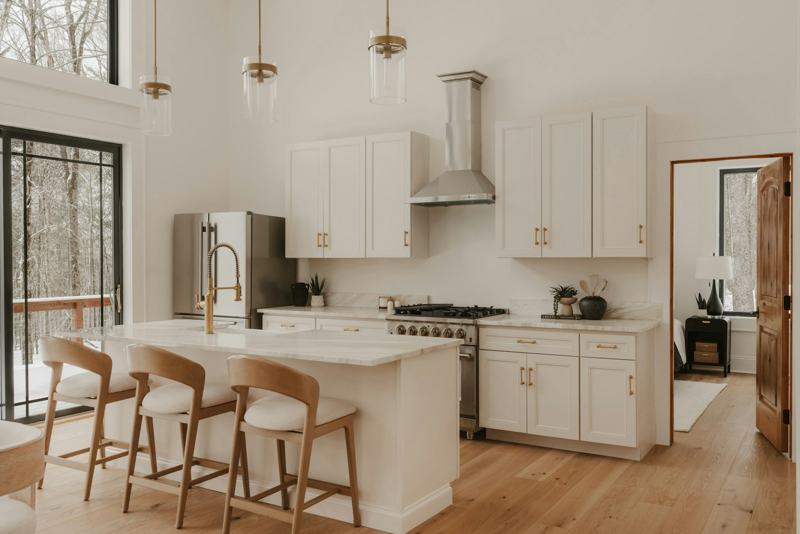 A clean white kitchen with an island and wooden stools