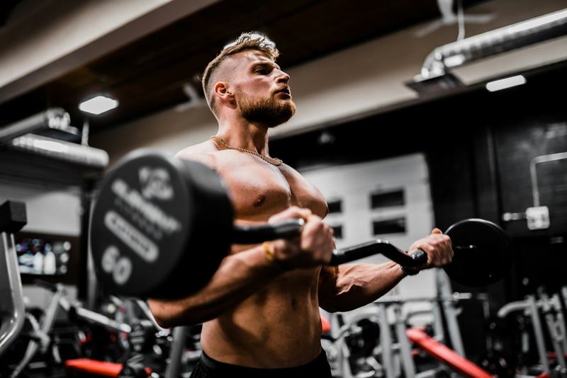 A man does barbell curls in a dim gym