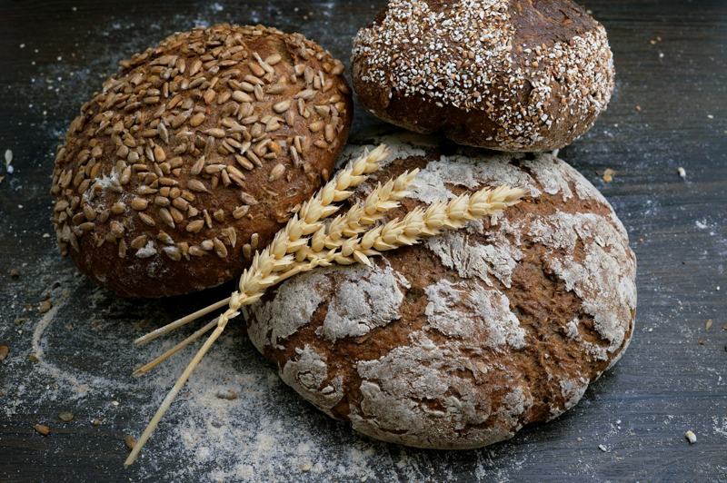 Rustic seeded loaves beside a sprig of wheat