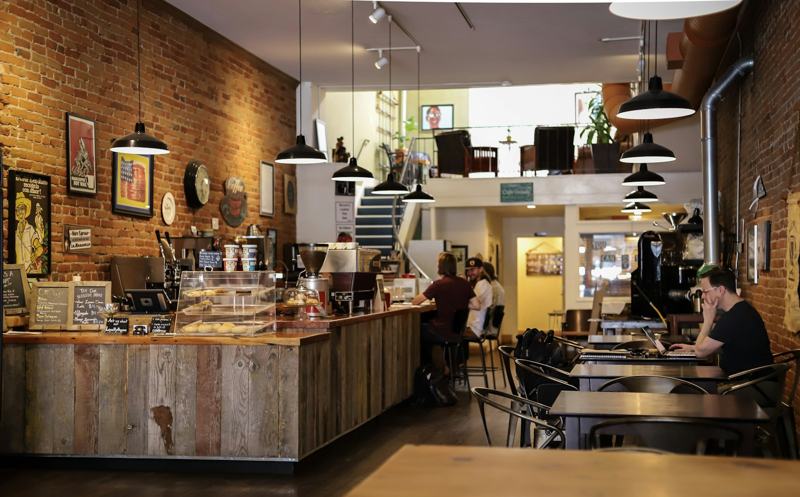 Café interior with a brick wall, wooden counter and people seated at tables