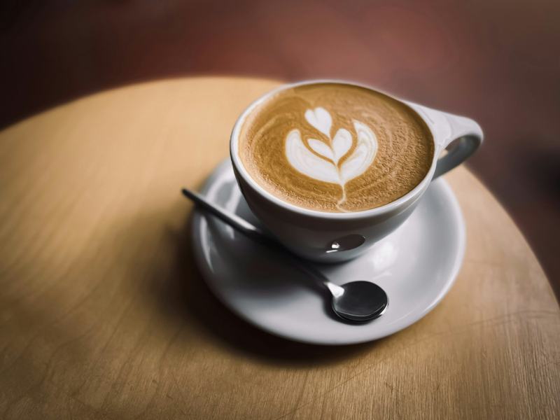 A latte with a leaf pattern on a wooden table