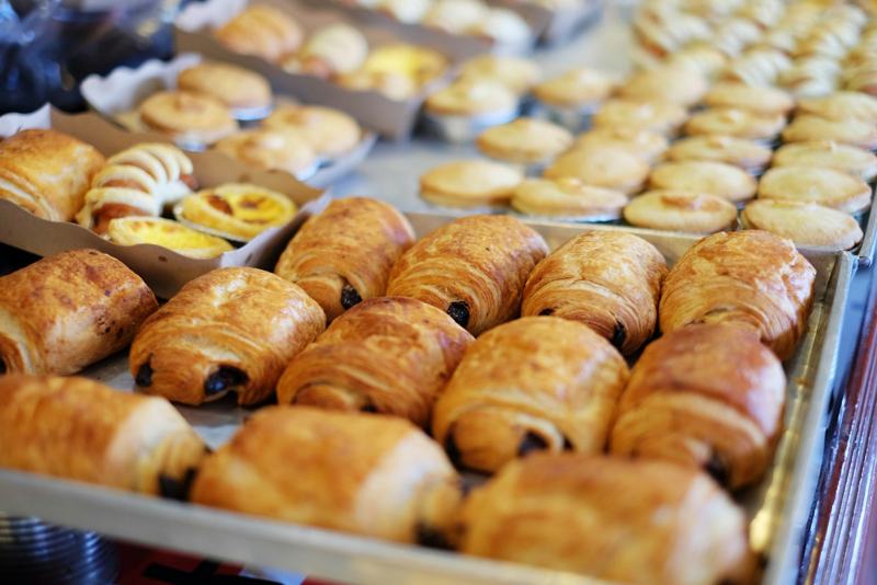 Trays of fresh pastries and tarts lined up in a bakery case